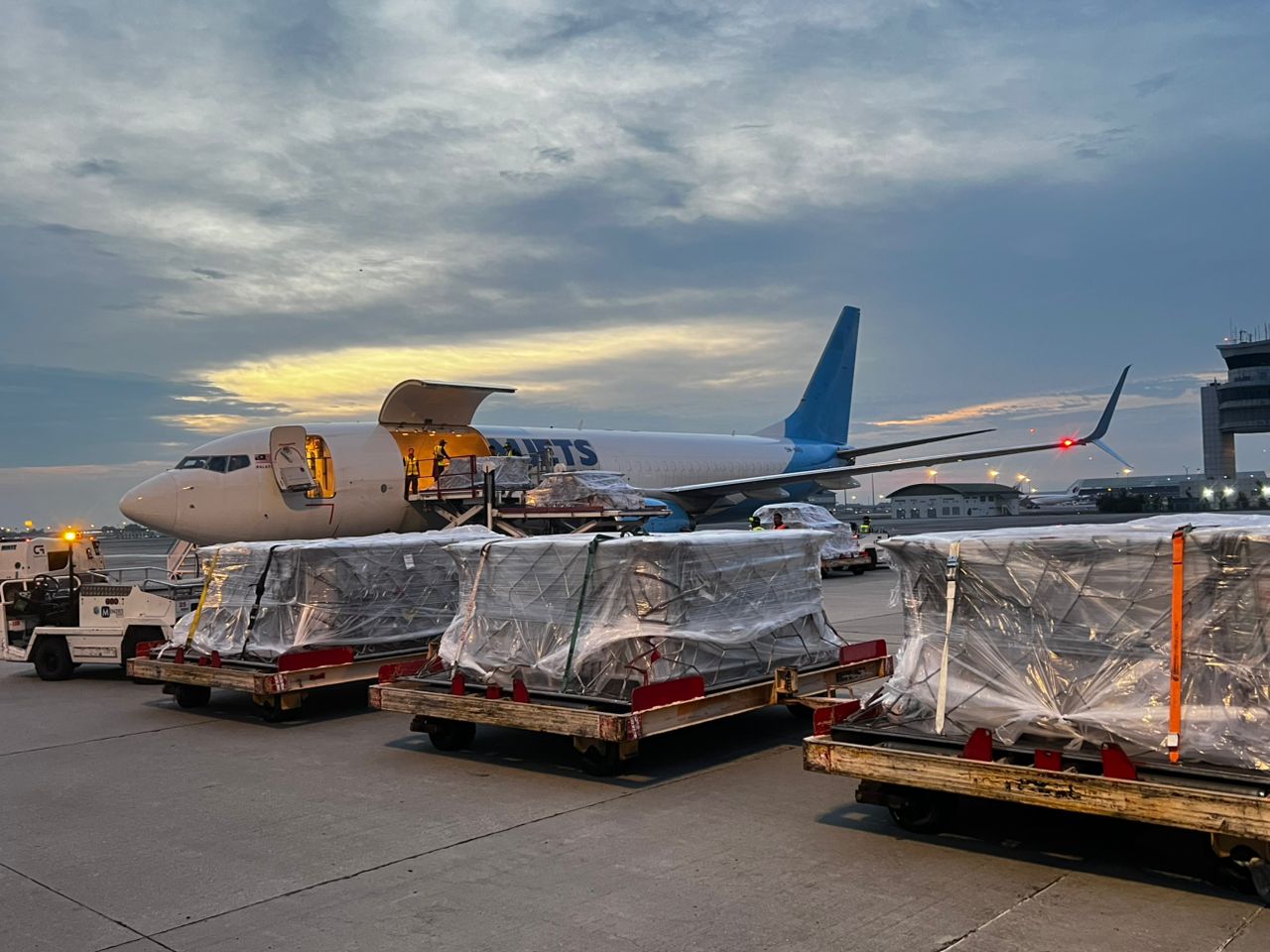 Freighter aircraft loading palletized cargo at dusk