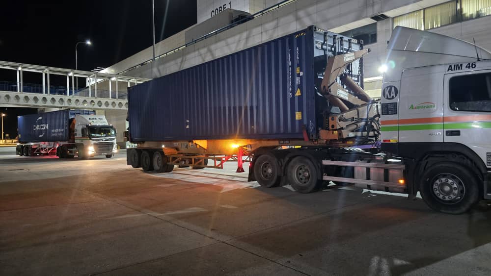 Container haulage trucks at a transshipment terminal at night