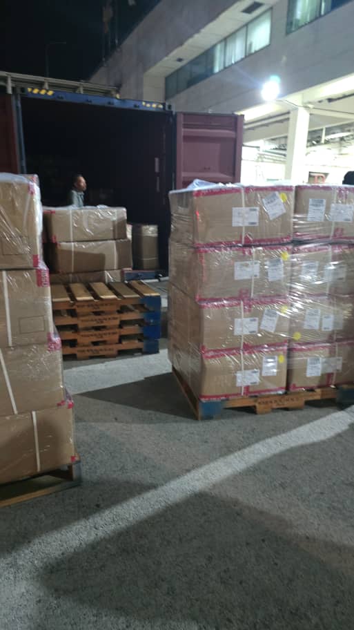 Palletized cargo being loaded into a container at night